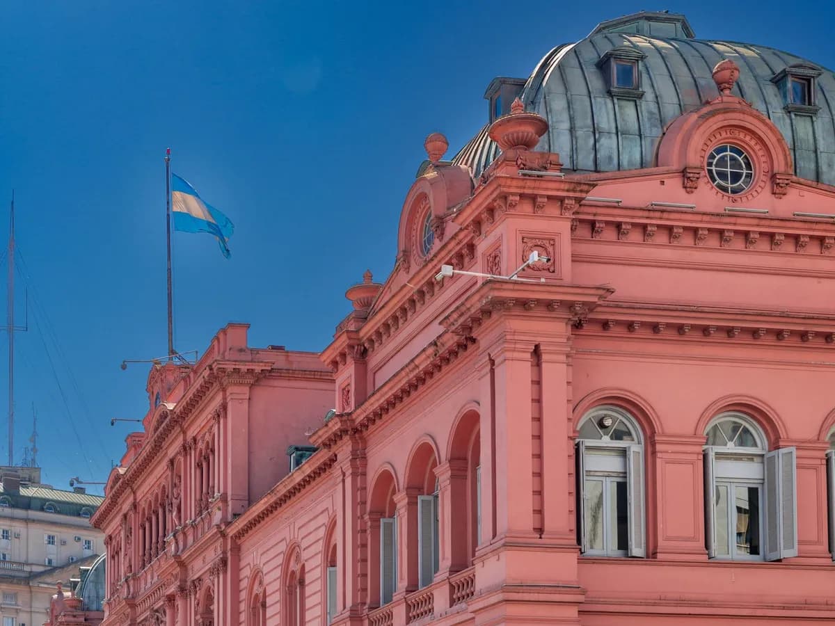 Cúpula de la Casa Rosada con la bandera argentina flameando bajo el cielo azul de Buenos Aires