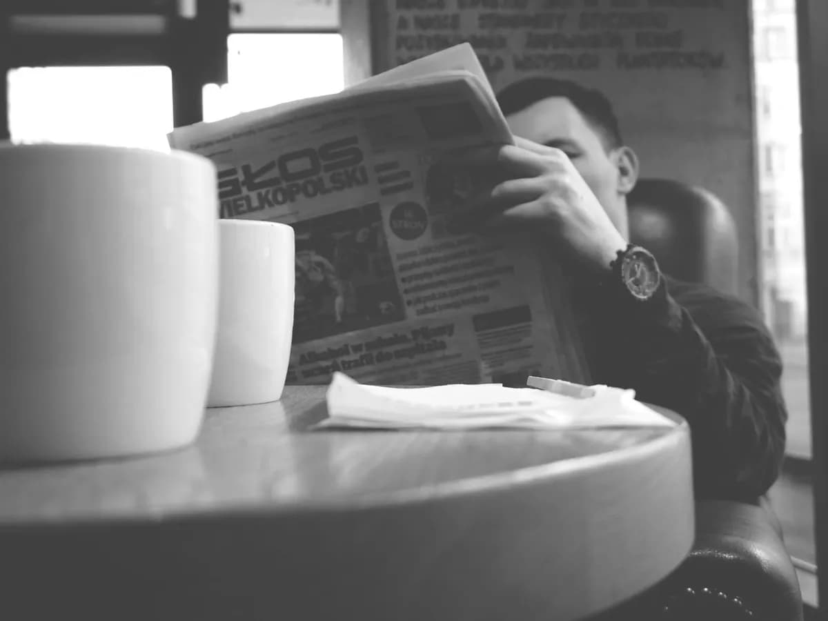Hombre leyendo el diario en un café, en blanco y negro